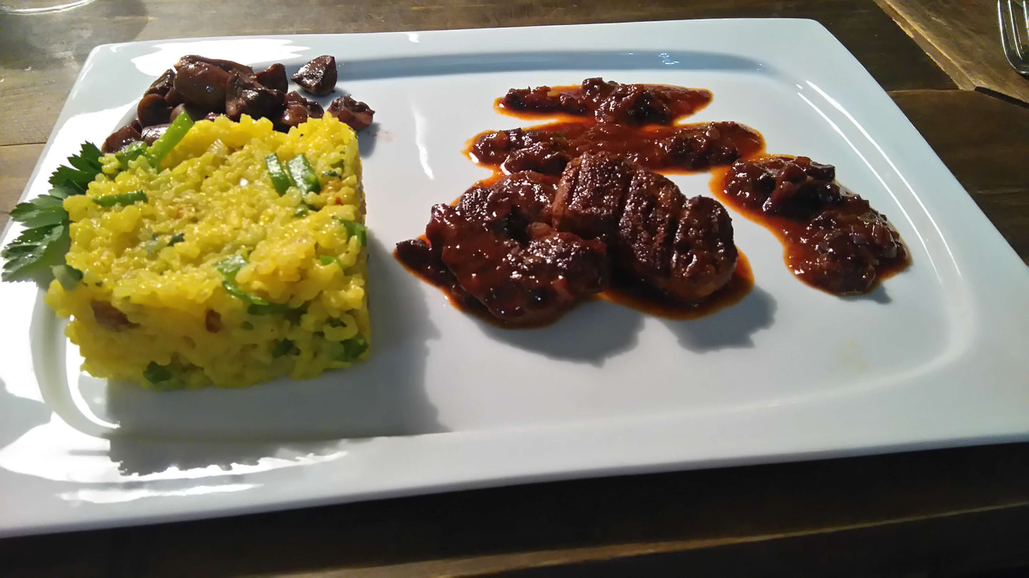 Safranreis und zartes Lamm in aromatischer Pflaumensauce – ein köstliches Beispielgericht aus dem spanischen Kochkurs in Düsseldorf, inspiriert von traditionellen iberischen Aromen.